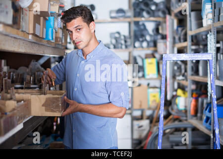 Junge Mann wählt kleine Details in den Feldern in einem Gebäude lagern Stockfoto