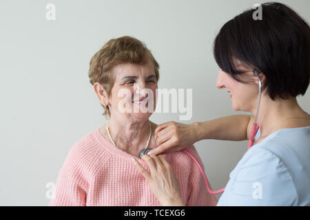 Krankenschwester mit authentischen lächelnden älteren weiblichen Patienten medizinische Prüfung Stockfoto