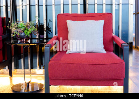 Closeup roter Baumwolle Sessel mit Polster in der Nähe von Schwarzen Kaffee Tisch im Wohnzimmer. Stockfoto