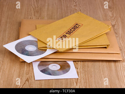 Umschläge mit top secret Stempel mit CD-Laufwerke auf Holz- Hintergrund Stockfoto