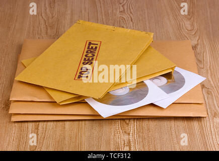 Umschläge mit top secret Stempel mit CD-Laufwerke auf Holz- Hintergrund Stockfoto