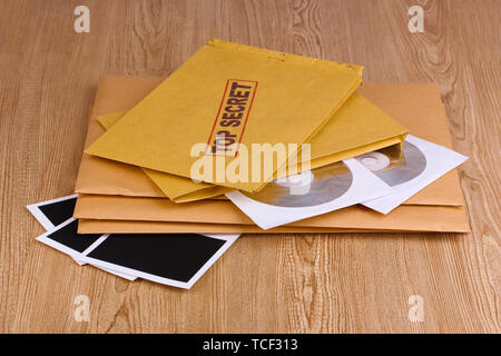 Umschläge mit top secret Stempel mit Fotopapier und CD-Laufwerke auf Holz- Hintergrund Stockfoto