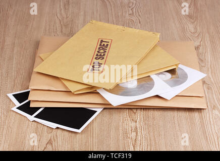 Umschläge mit top secret Stempel mit Fotopapier und CD-Laufwerke auf Holz- Hintergrund Stockfoto