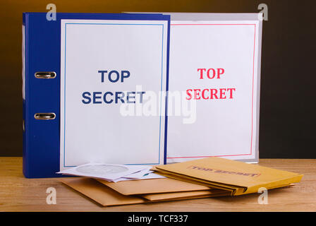 Umschläge und Ordner mit top secret Stempel- und CD-Laufwerke auf Holztisch auf braunem Hintergrund Stockfoto