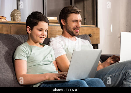 Lächelnd Sohn und Papa mit Laptops im Wohnzimmer Stockfoto