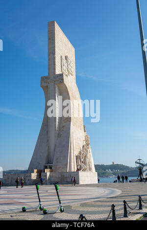 Lissabon, Portugal - 19. Februar 2019: Zwei grüne Elektroroller vor dem Denkmal der Entdeckungen an einem sonnigen Tag und blauer Himmel. Stockfoto