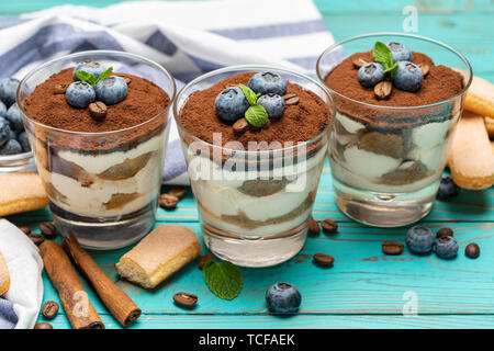 Classic Tiramisu Dessert in ein Glas mit Blaubeeren auf Blau Holz- Hintergrund Stockfoto