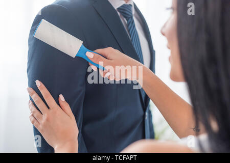 7/8-Ansicht von Mann mit brunette Mädchen holding Fussel Roller in der Nähe von formalen Verschleiß Stockfoto