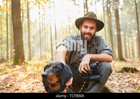 Förster mit Jagdhund und Fernglas nimmt einen Bruch in seinem Wald Stockfoto