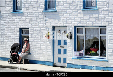 Eine Frau sitzt in Doonbeg Dorf, County Clare, vor uns Präsident Donald Trump Ausgangspunkt für Shannon Flughafen. Stockfoto