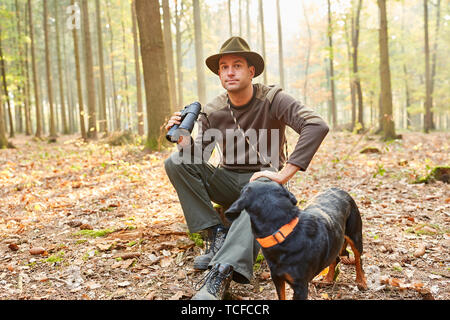 Förster oder Jäger mit Hund als Jagdhund und Ferngläser im forstwirtschaftlichen Bereich Stockfoto