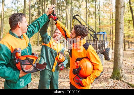 Gruppe Wald Arbeiter feiert als Team mit einem hohen fünf nach der Holzernte Stockfoto