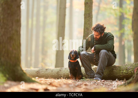 Hund als Jagdhund zusammen mit einem Jäger oder Förster eine Pause im Wald Stockfoto