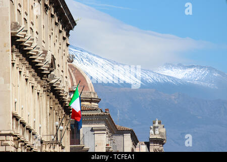 Historische Gebäude in Catania, Sizilien, Italien mit Winkenden italienischen Flagge. Im Hintergrund die Kuppel der berühmten Hl. Agatha Kathedrale und den Ätna mit Schnee auf der Spitze des Vulkans. Stockfoto