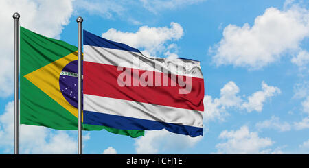 Brasilien und Costa Rica Flagge im Wind gegen Weiße bewölkt blauer Himmel zusammen. Diplomatie Konzept, internationale Beziehungen. Stockfoto