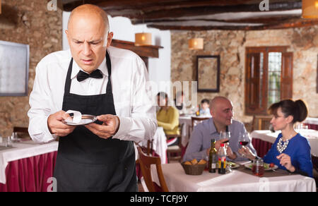 Männliche Kellner demonstriert seine umgekippt mit kleinen Tipps vom Restaurant Besucher Stockfoto