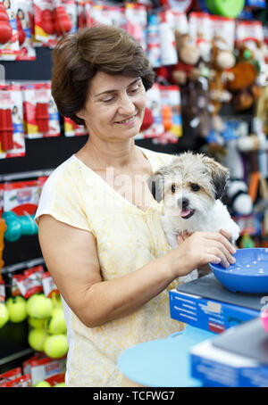 Portrait von gerne ältere Frau besuchen Pet Supplies Store mit ihren niedlichen Welpen von havaneser Stockfoto