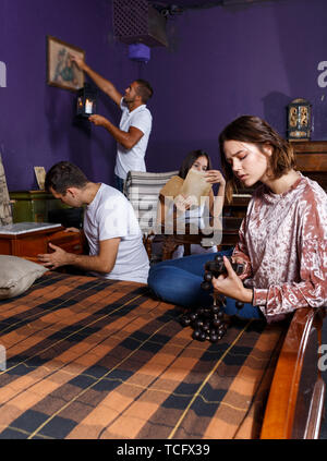 Gruppe von jungen Erwachsenen, die Inspektion von Holz- Rosenkranz, die versuchen, die Lösung des Rätsels in Flucht- Zimmer mit antiken Möbeln zu finden Stockfoto