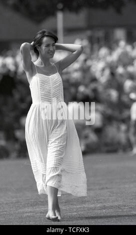 In Uxbridge Middlesex CCC Cricket 1990 eine junge Frau, die auf dem Boden während der Mittagspause in einer fließenden weißen sommerliches Kleid. Foto von Tony Henshaw Stockfoto