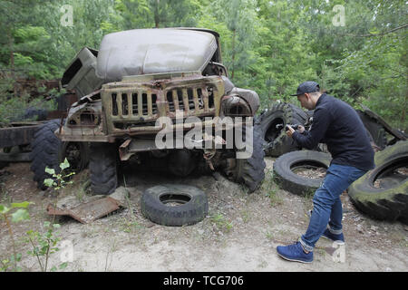 Pripyat, Ukraine. 7. Juni 2019. Ein Besucher nimmt Fotos eines havarierten auto in die Sperrzone von Tschernobyl in der verlassenen Stadt Pripyat. Der HBO-TV-Miniserie Tschernobyl, in den USA und in England im Mai 2019 uraufgeführt, schildert die Zeit nach der Katastrophe, einschließlich der Reinigung und die anschließende Untersuchung. Credit: ZUMA Press, Inc./Alamy leben Nachrichten Stockfoto