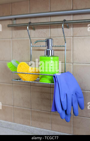 Besteck, Geschirr, flüssig, Handschuhe, Bürste, Schwamm auf Metall Regal in der Küche. Konzept der dekantieren Waschmittel, keine Etiketten und visueller Lärm. Stockfoto