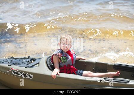 Ein kleiner Junge sitzt in einem Kajak an der Küste der Bucht Stockfoto