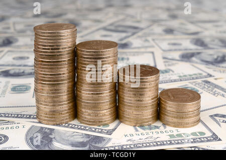 Stapel der ukrainischen Münzen im Stapel nach unten fallen. Ukrainische Geld liegt auf uns Hundert-Euro-Scheine Stockfoto