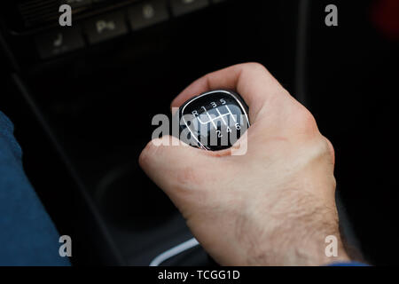 Mann Hand an einem mechanischen Getriebe im Auto. Mann fahren Auto. Auto Details im Innenraum. Auto 6-Gang-Getriebe Stockfoto