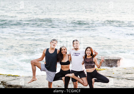 Gruppe von Menschen, die Yoga Übungen und lächelnd auf den Strand Stockfoto