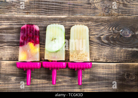 Hausgemachte Vegan Popsicle aus gefrorenen Apfelsaft und Beeren, Äpfel und Cookies auf dunklen rustikalen Hintergrund. Sommer essen Konzept. Ansicht von oben. Kopieren Raum f Stockfoto