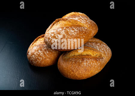 Frisch gebackene leckere Brot auf einem dunklen Tisch. Leckere Backwaren direkt aus der Bäckerei. Schwarzen Hintergrund. Stockfoto