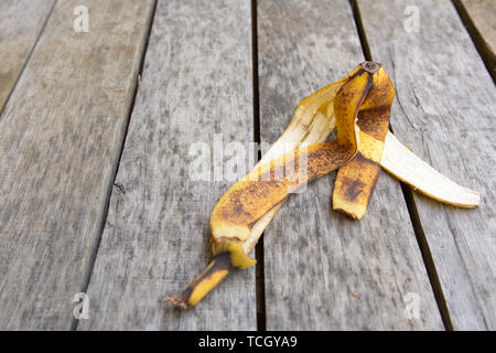 Braun und Gelb zerknittert Bananenschale liegen auf alten Grau mit dunklen Flecken, Holz- Oberfläche Stockfoto