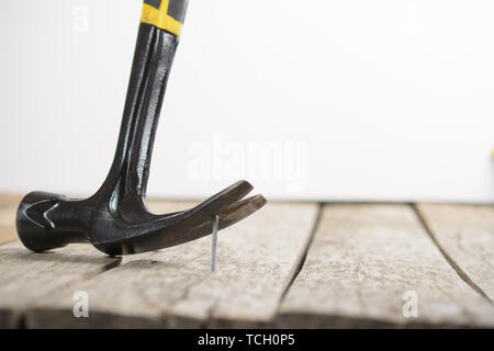 Hammer Neugierigen einen Nagel aus einem Holz Plank. Stockfoto