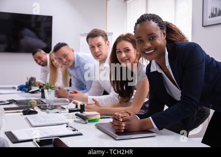Multiethnische Gruppe von Happy Geschäftsleute zusammen In der Reihe sitzen an Kamera suchen Stockfoto