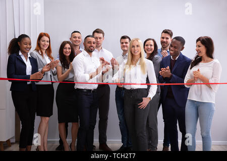 Lächelnd erfolgreiche Geschäftsfrau, die Red Ribbon mit Ihrem Personal Stockfoto