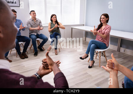 Gruppe von Jugendlichen lernen Gehörlose Geste Zeichen von Frau sitzt auf Stuhl Stockfoto