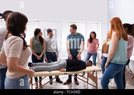 Männliche Kursleiter Lehre Massagetechnik zur Gruppe der multi-ethnischen Menschen Stockfoto