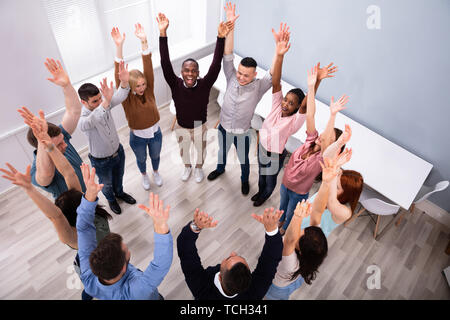Multirassischen tausendjährigen Menschen im Kreis heben ihre Hände zusammen Stockfoto