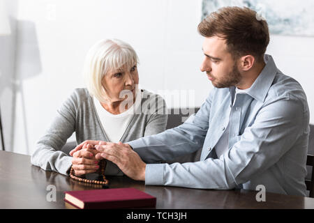 Ältere Frau mit Rosenkranz Hände mit Sohn Stockfoto