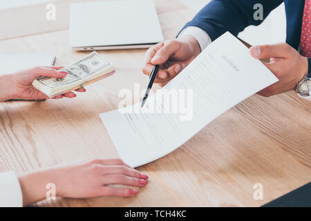 Teilweise mit Blick auf die Unternehmer bei Unterschrift Ort, die im Darlehensvertrag in der Nähe von Frau mit Dollar Banknoten Stockfoto