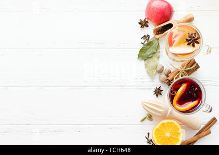 Zwei Gläser verschiedener Art von Glühwein oder Glühwein auf Rot- und Weißwein mit Gewürzen und Zutaten auf weißem Holz- Hintergrund basiert. Hot seaso Stockfoto
