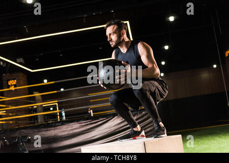 Low Angle View ernsthafter Sportler tun Hocke auf hocken, während die Kugel Stockfoto