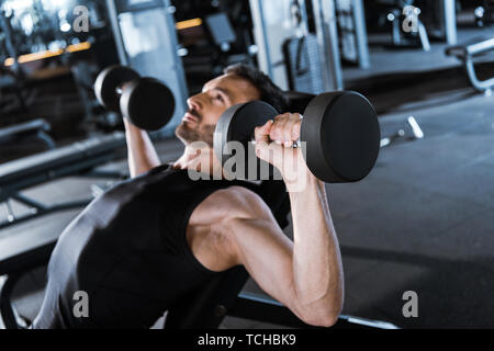 Selektiver Fokus der bärtige Mann heraus arbeiten mit Hanteln in der Turnhalle Stockfoto