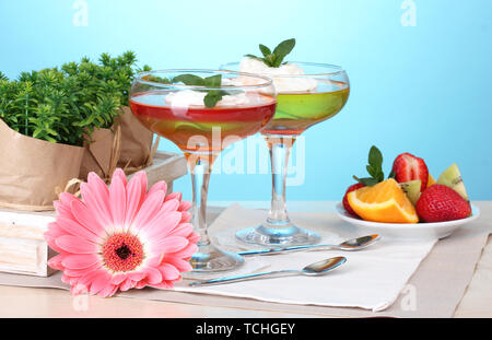 Grütze in Gläsern und Früchte auf dem Tisch auf blauem Hintergrund Stockfoto