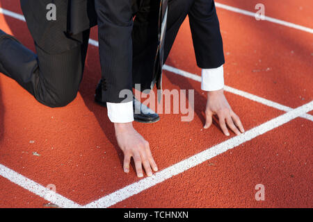 Business Mann warten auf den Start Signal am Wettbewerb Laufbahn zu starten Stockfoto