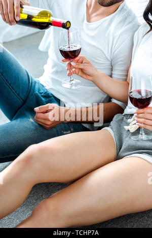 7/8-Ansicht von Paar trinken Rotwein aus Gläsern Stockfoto