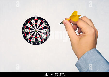 Die menschliche Hand ist das Werfen der darts Target, um die Dartscheibe. die Hand eines Mannes wirft einen Pfeil auf die Zielscheibe. Stockfoto