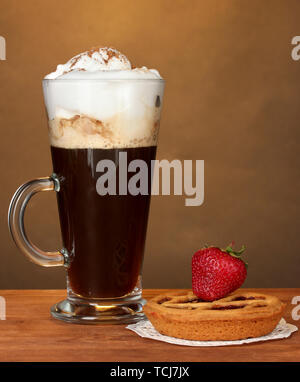 Glas Kaffee Cocktail mit tart auf deckchen und Erdbeere auf braunem Hintergrund Stockfoto