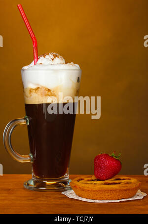 Glas Kaffee Cocktail mit tart auf deckchen und Erdbeere auf braunem Hintergrund Stockfoto