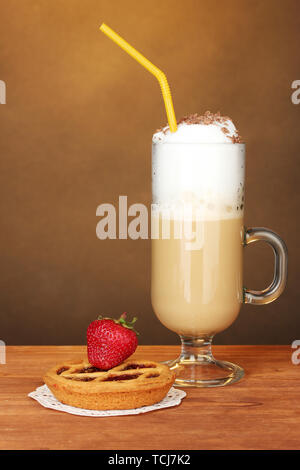 Glas Kaffee Cocktail mit tart auf deckchen und Erdbeere auf braunem Hintergrund Stockfoto